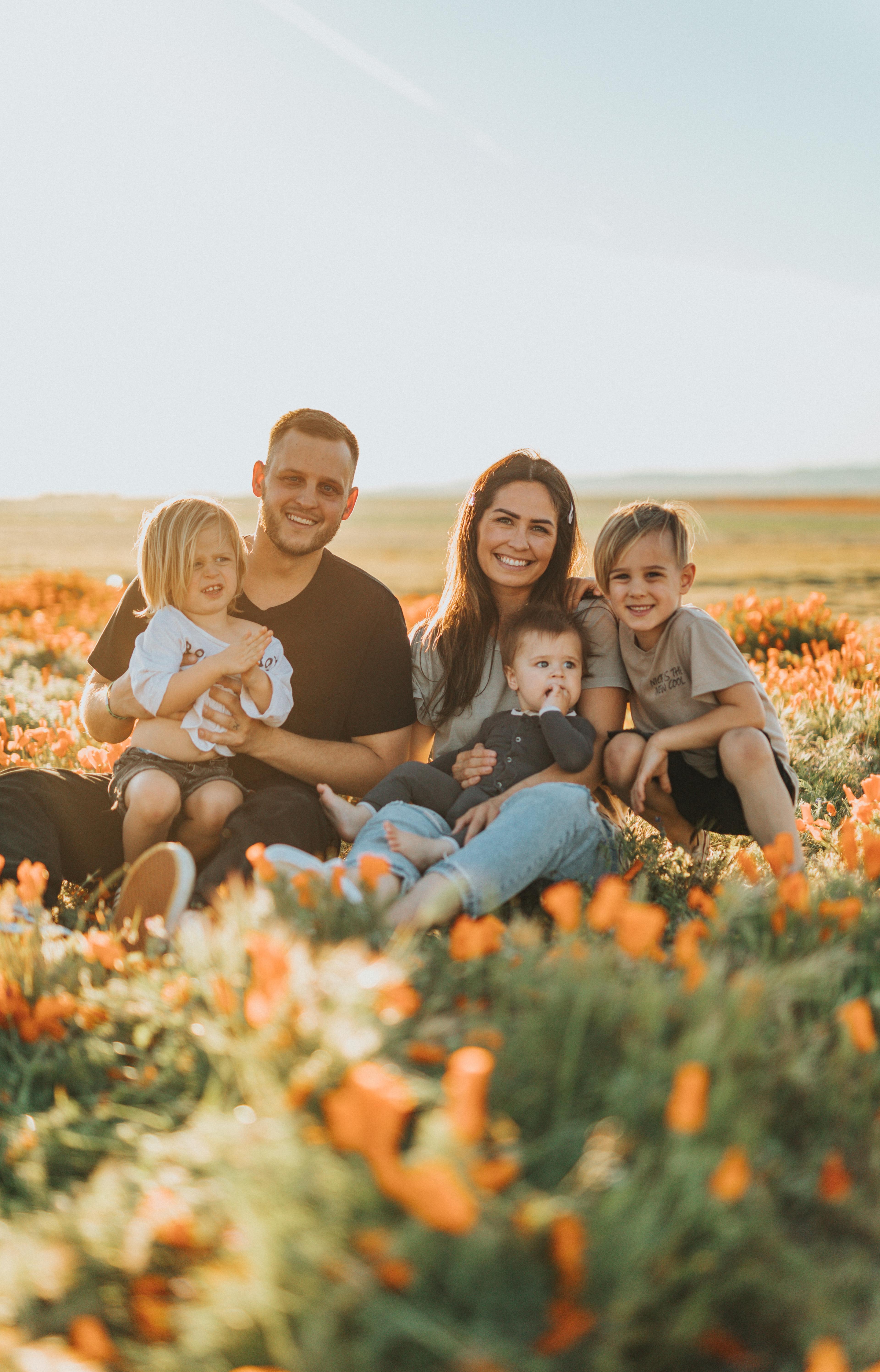 family sitting on grass field. Father and Mother with three kids