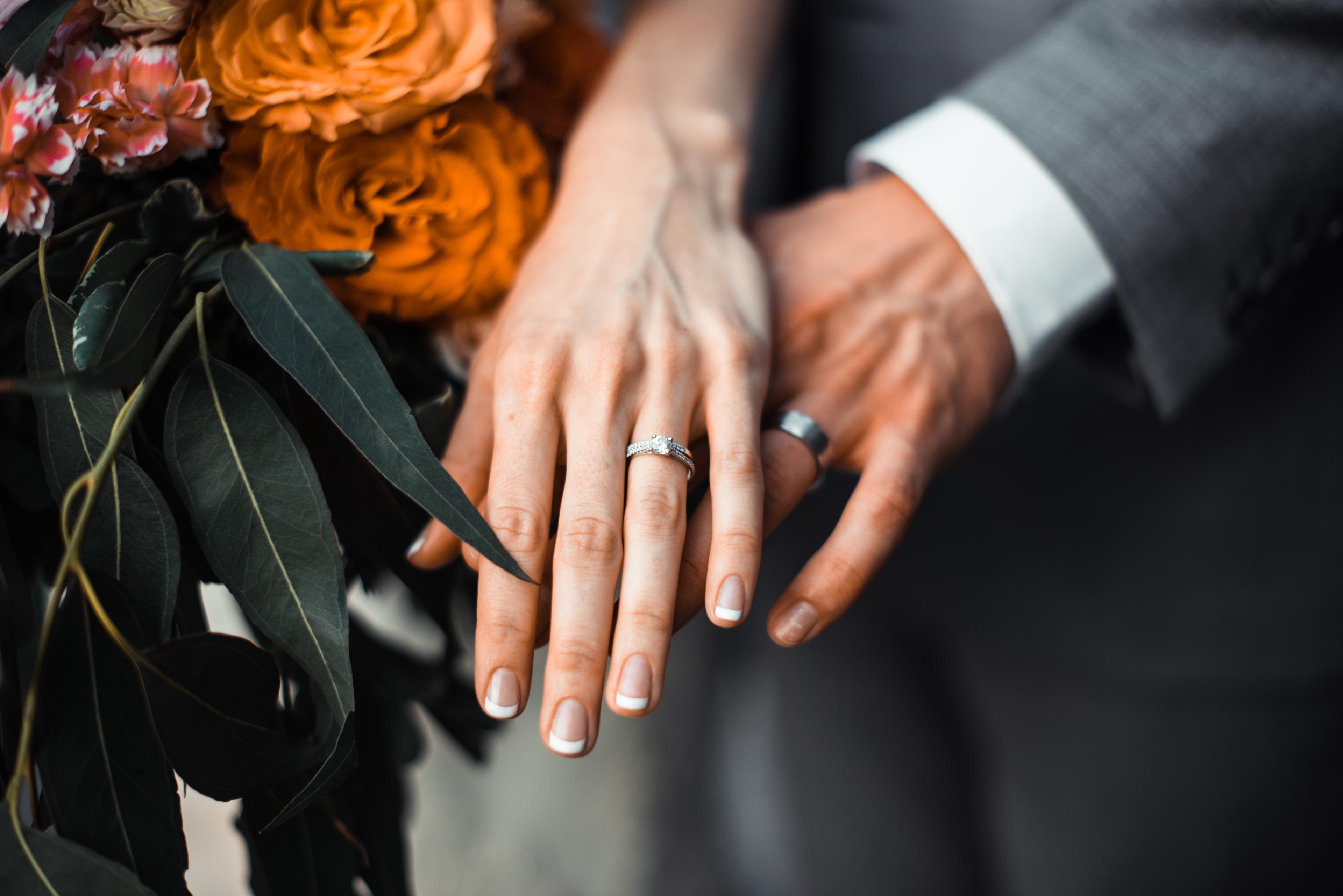 bride and groom showing off left hands with rings on